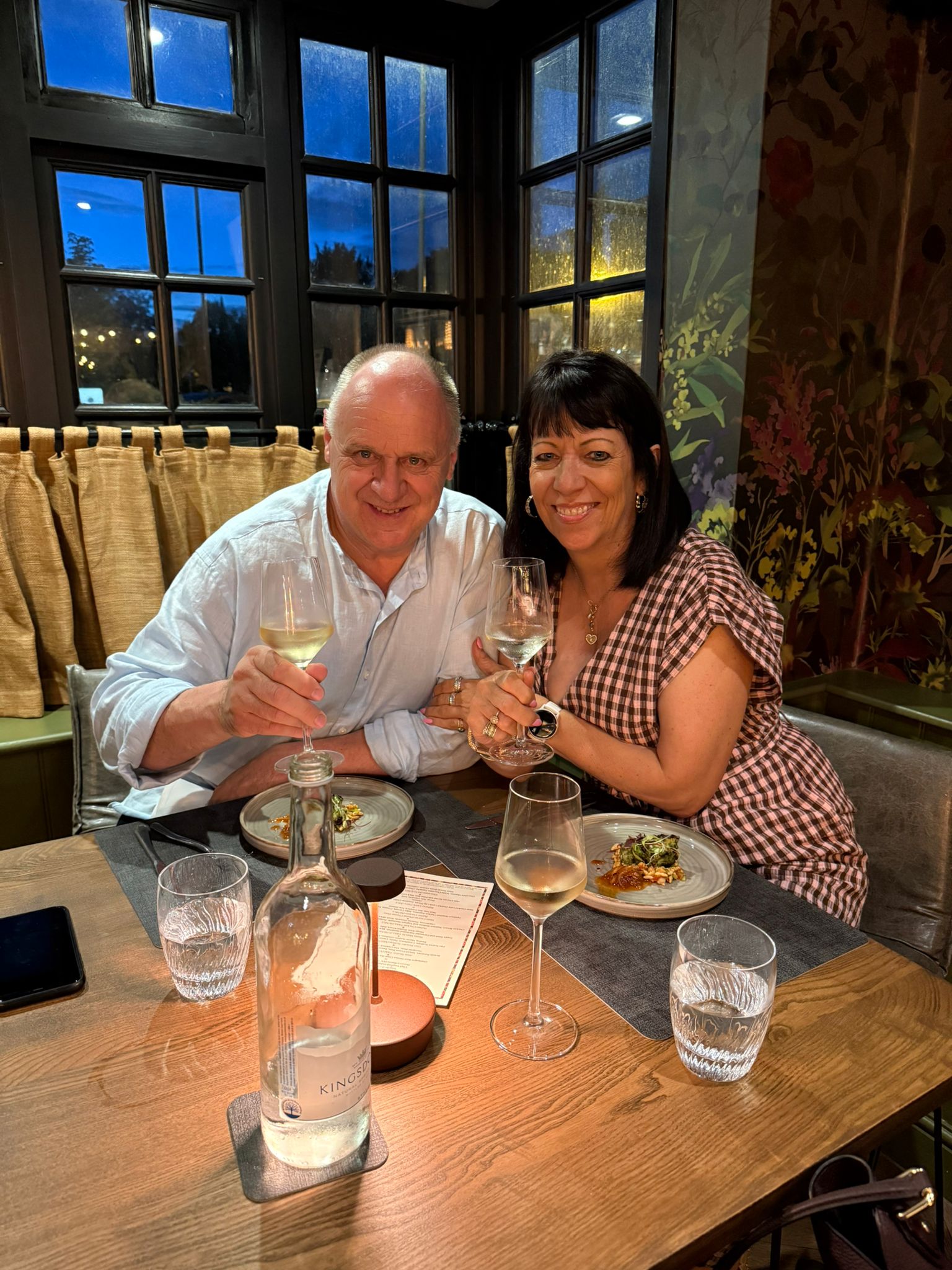 Mark and Carolyn smiling together over dinner at Vaasu